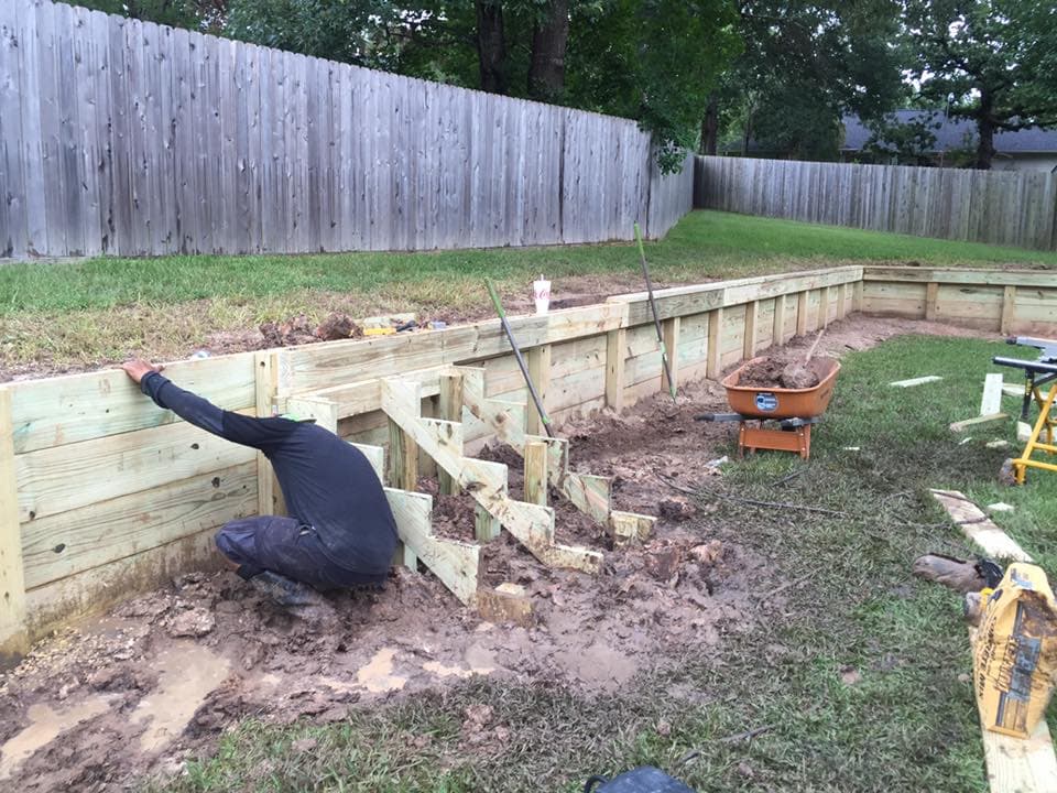 Rockin' D Services crew building a wood retaining wall, showing post and board framing mid-installation