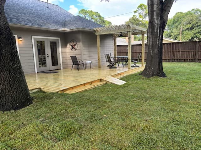 Finished wood deck with pergola and patio furniture, an outdoor gathering space built by Rockin' D Services in Huntsville, TX