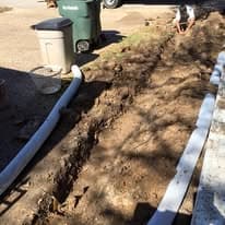 Completed drainage channel with rock lining and catch basin installed in a Walker County, TX yard