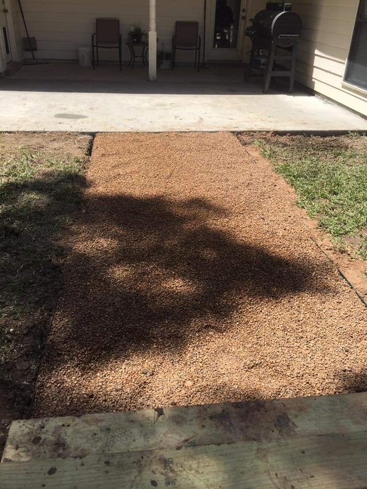 Gravel drainage bed installation beside a concrete patio to improve yard water flow in Huntsville, TX