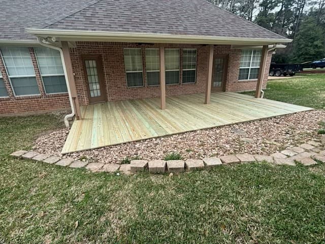 Ground-level wood deck attached to a covered patio at a brick home in Huntsville, TX