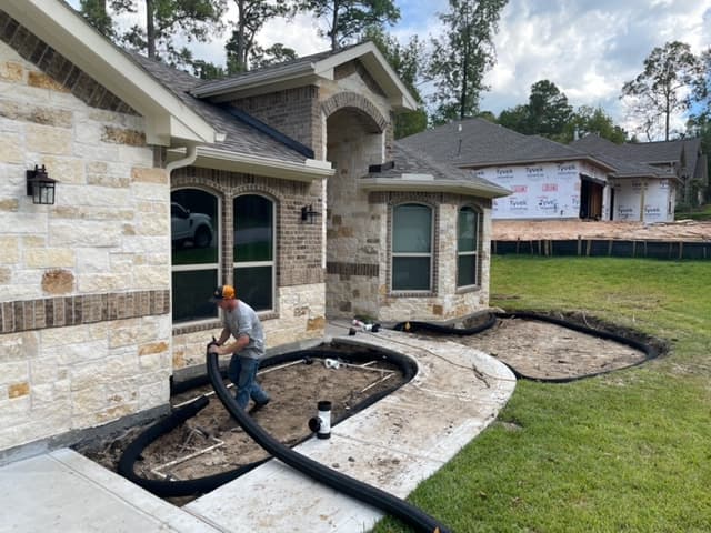 Curved flower bed borders with irrigation lines being installed at a new-construction home in Huntsville, TX