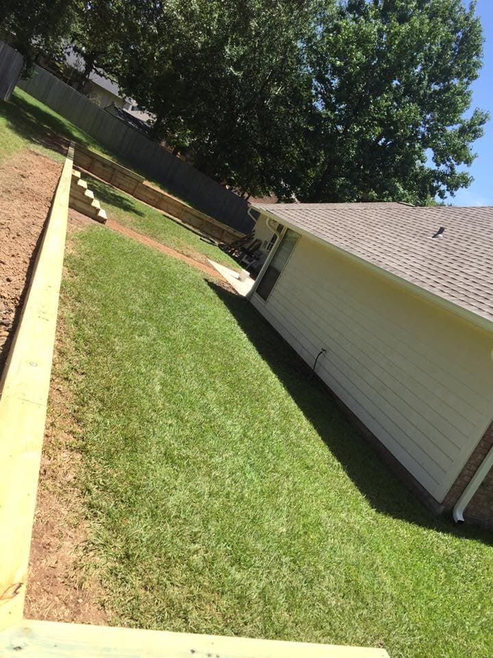Wood retaining wall terracing a sloped backyard beside a Huntsville, TX home