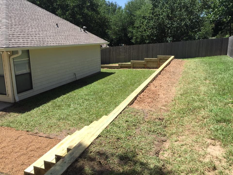 Aerial view of a long tiered wood retaining wall with built-in steps spanning a sloped yard