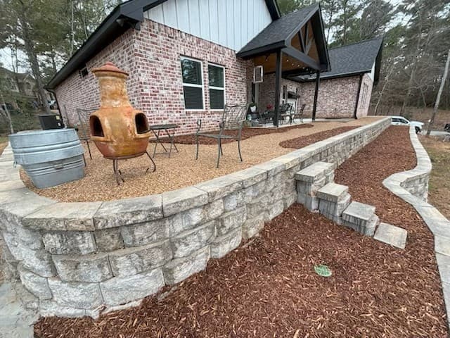 Segmental block retaining wall and mulched planting bed built behind a brick home in Huntsville, TX