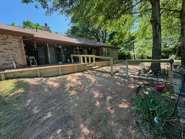 Wood deck with railing and retaining wall built onto the back of a brick ranch home in Huntsville, TX