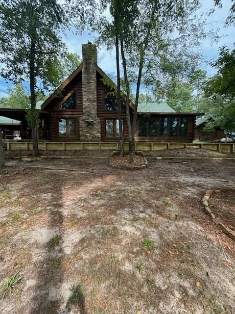 Wood retaining wall built around the base of a log cabin home with a stone chimney in Huntsville, TX