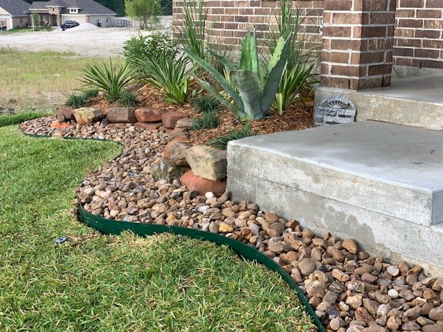 Decorative rock landscaping and planting bed installed by Rockin' D Services in Huntsville TX