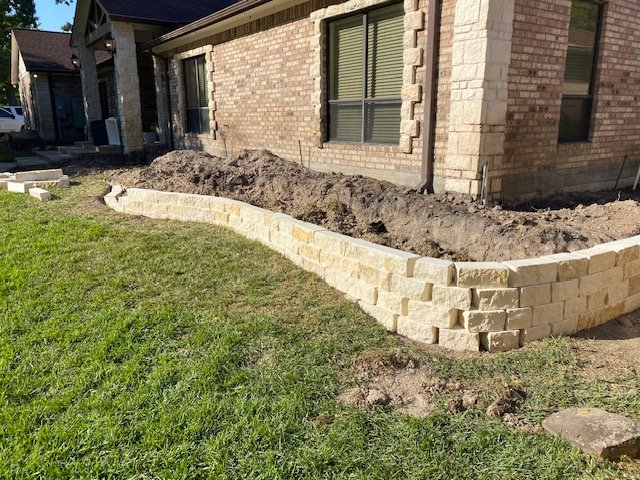 Custom limestone retaining wall and landscape installation by Rockin' D Services in Huntsville TX